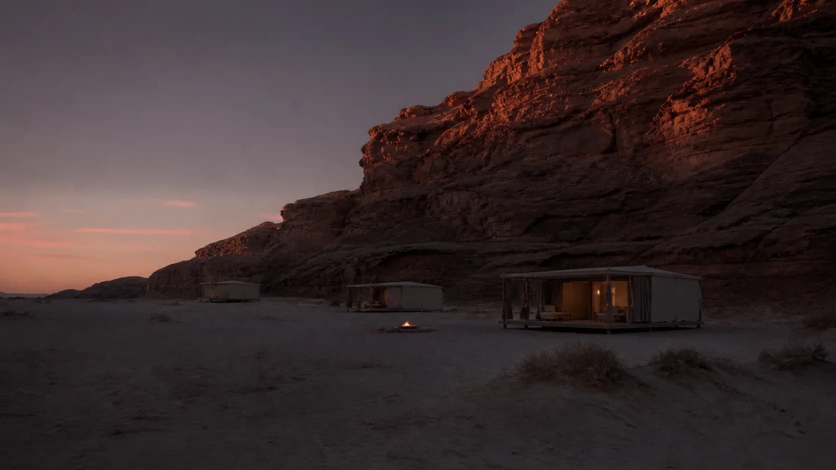 The Sabaia escarpment lit red above grey desert sand at sunset.
