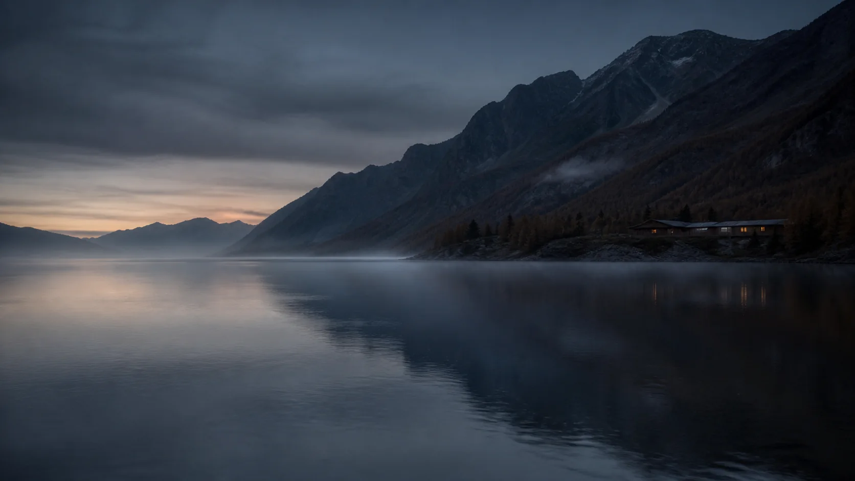 Lake Verane before sunrise, mist lying flat on the water beneath dark ridges.