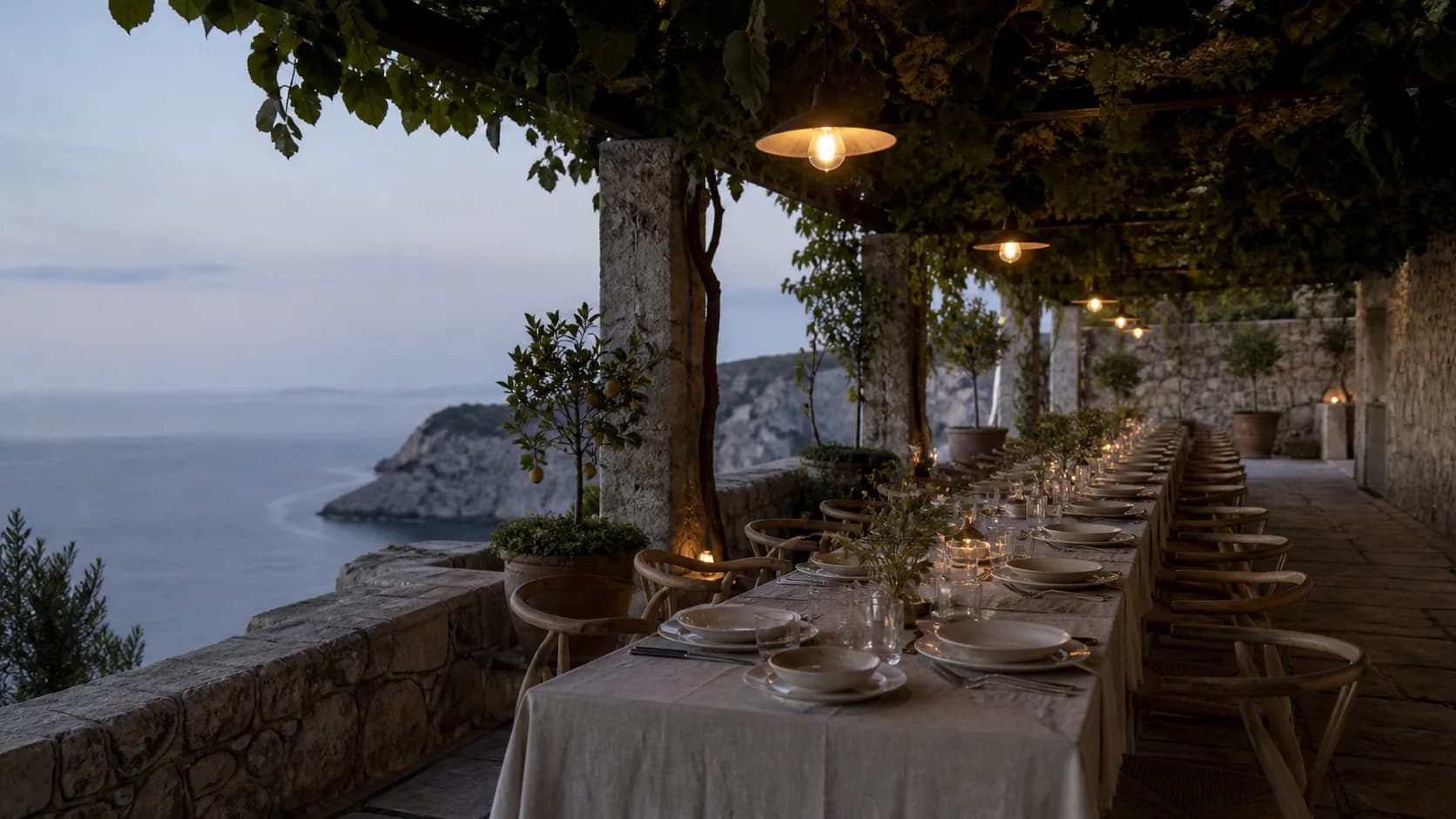 A long wedding table beneath the vine pergola on Calanera's Second Terrace at blue hour.