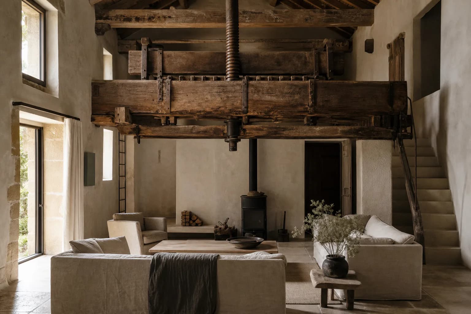 The double-height living room of The Old Press at Maison Aubris beneath its original beam press.